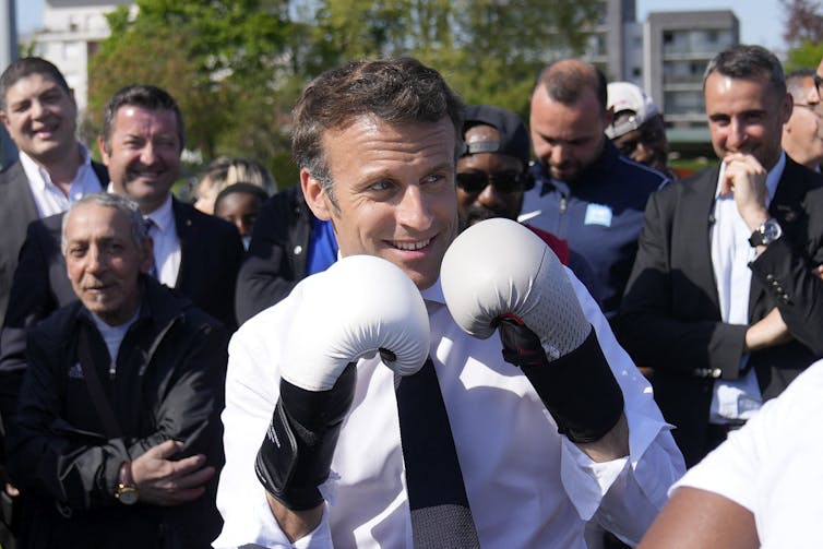 Emmanuel Macron porte des gants de boxe alors qu’il rencontre un boxeur local lors d’une visite de campagne à Saint-Denis, en banlieue parisienne le 21 avril 2022